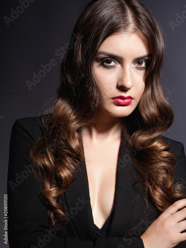 Girl model with hair and makeup in black clothes on a dark background in the studio