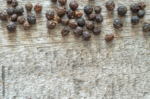 Black pepper corns on wooden background, copy space.