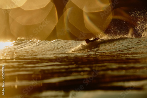 a surfer paddles for a wave at dusk photo