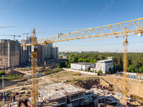 yellow building cranes on construction site against blue sky background