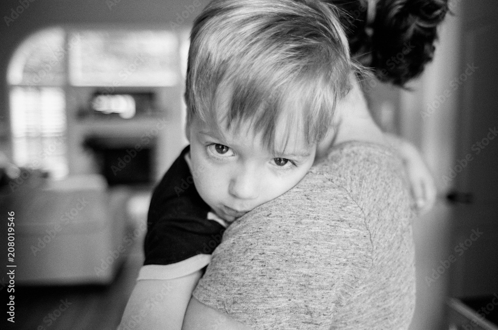 Cute young boy resting on his mother's shoulder Cute young boy resting on his mother's shoulder