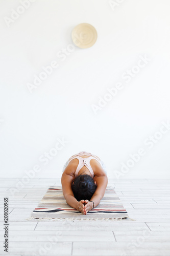 charming young unknown woman a yoga instructor doing an exercise - Triang Mukha Ekpada Pashchimotanasana on a rug In the modern gym. Copyspace photo