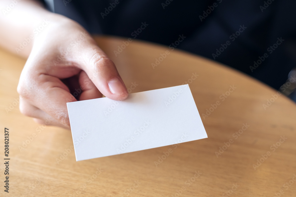 Businesswoman holding and giving an empty business card to someone on table in office Businesswoman holding and giving an empty business card to someone on table in office