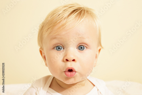 Close up portrait of cute baby with blonde hair looking surprised in his crib photo
