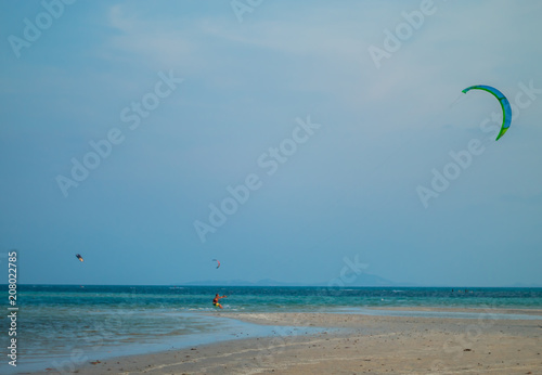 Tourists enjoy Kitesurfer surfing in the sea.