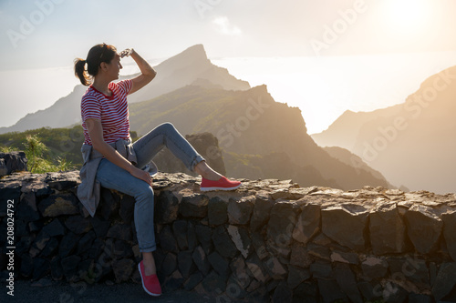 tourist girl looking at mountains and sunset photo