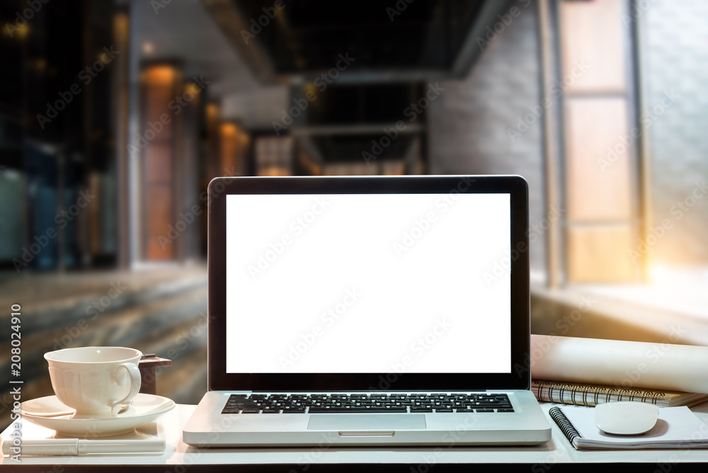 Fototapeta premium Front view of cup and laptop on table in office and background in the coffee shop and restaurant