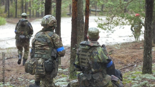 Soldiers in camouflage with combat weapons are being fired in the shelter of the forest, the military concept photo