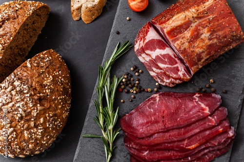 Smoked meat with ingredients on the black stone board