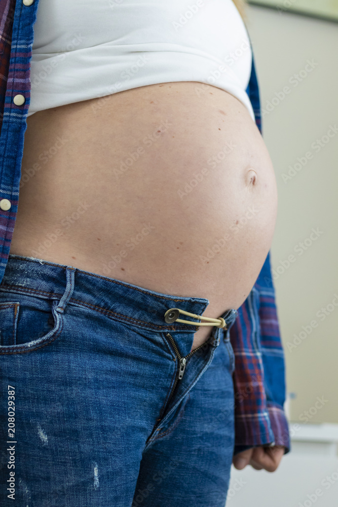 A Large Pregnant Belly not fitting in Jeans foto de Stock | Adobe Stock