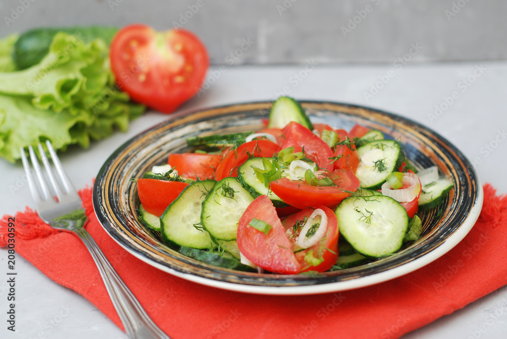 Tomato and cucumber salad vegan food with fork gray textured cement background Tomato and cucumber salad vegan food with fork gray textured cement background