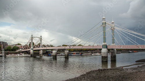 Albert Bridge over river Thames in London on gray overcast day. It connects Chelsea to Battersea and was opened in 1873