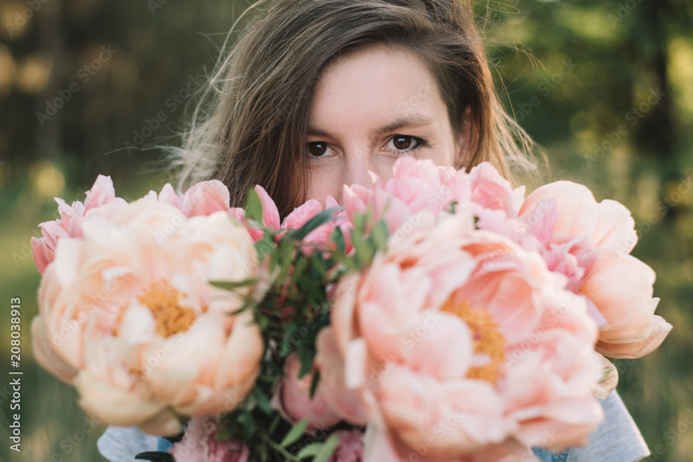 Fototapeta premium Florist woman looking over peony flowers