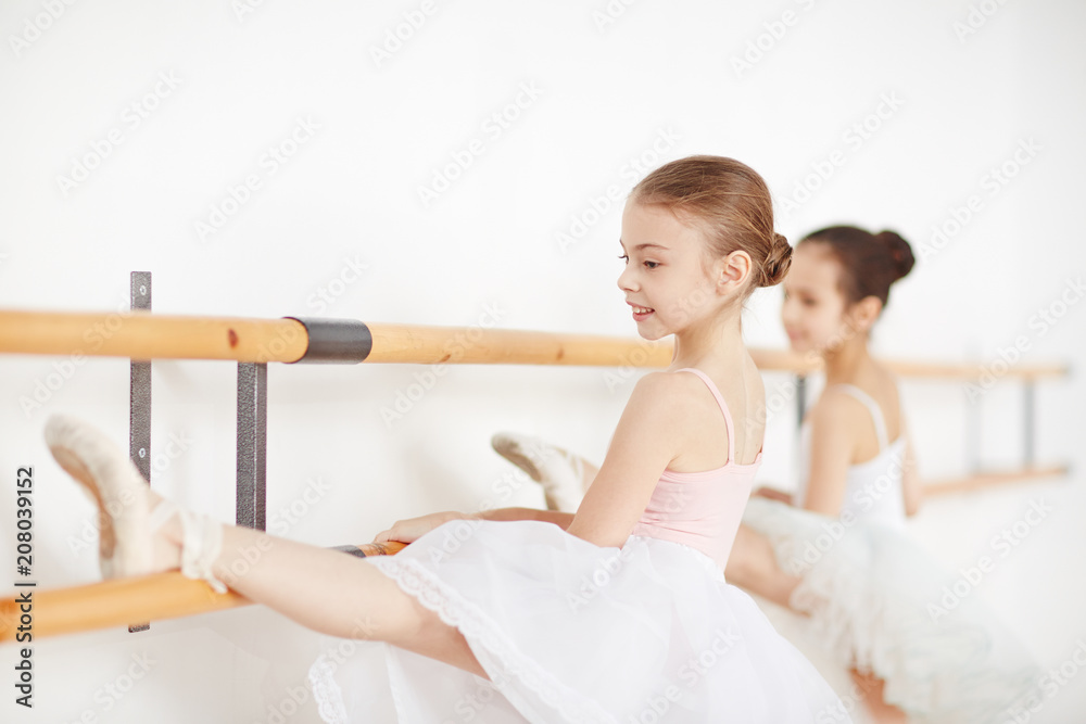 Little ballerinas practicing dances at wooden machine and smiling side view Little ballerinas practicing dances at wooden machine and smiling side view