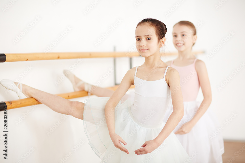young girls in white clothes and pointe making stretching in dancing school side view young girls in white clothes and pointe making stretching in dancing school side view