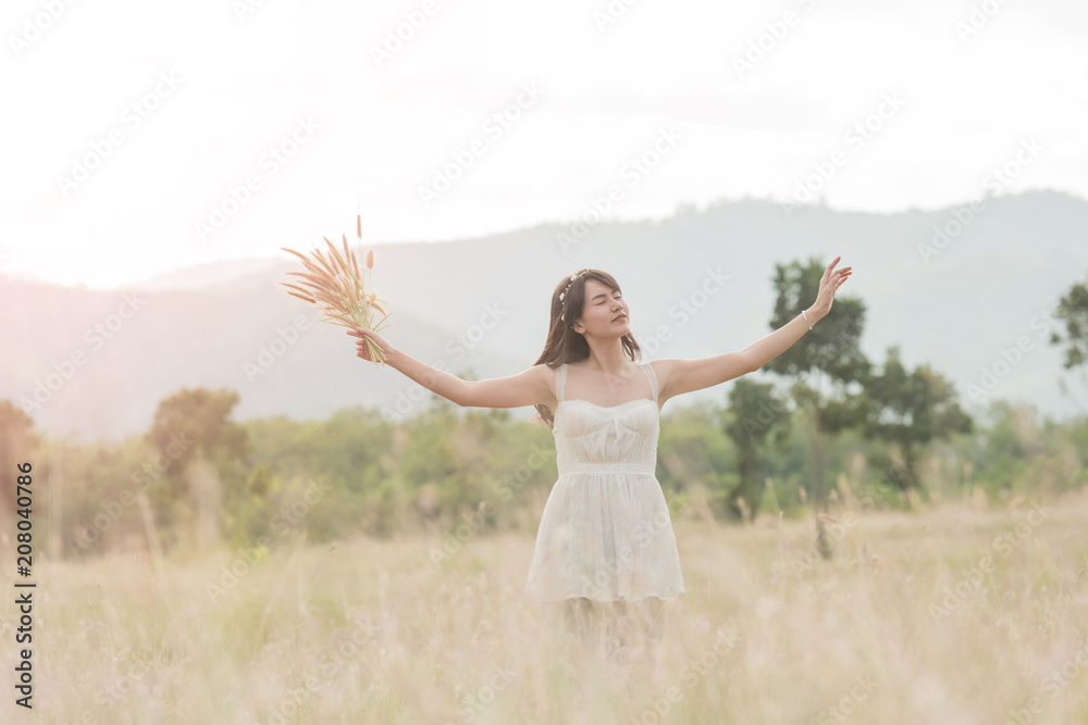 Beautiful woman enjoying meadow field, nice female lying down in meadow of flowers, pretty girl relaxing outdoor, having fun, holding plant, happy young lady and spring green nature, harmony concept