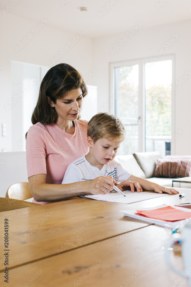 Young Caucasian Mother Drawing With Her Son at Wooden Table in Bright Apartment Young Caucasian Mother Drawing With Her Son at Wooden Table in Bright Apartment