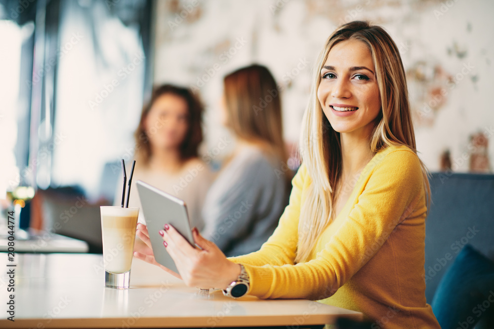 Young caucasian woman using tablet while sitting in cafe and drinking coffee. Young caucasian woman using tablet while sitting in cafe and drinking coffee.