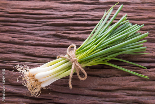 Spring onions also known as salad onions, green onions or scallions on wood background