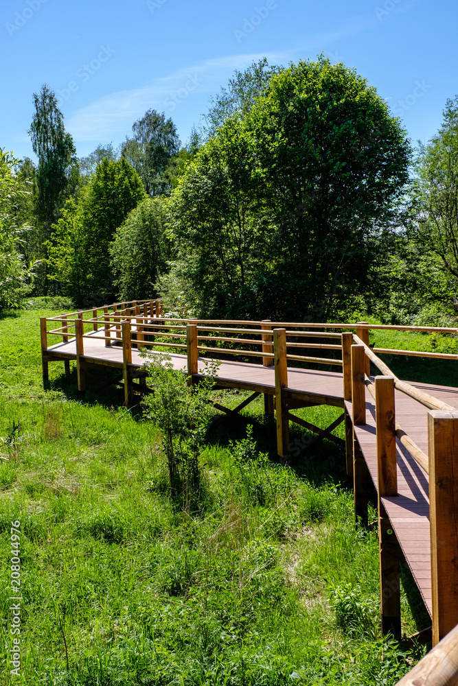 wooden boardwalk in green meadow area wooden boardwalk in green meadow area