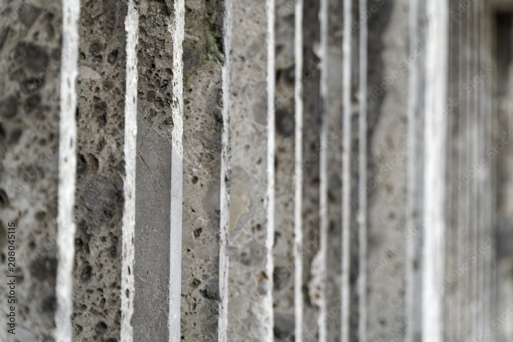 Fototapeta premium Stone fence with parallel concrete poles and old green moss