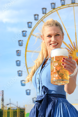 young sexy woman women girls is doing oktoberfest spring festival. she is holding a bier and a prezel in her hand beautiful summer sun blue sky and nice dirndl photo