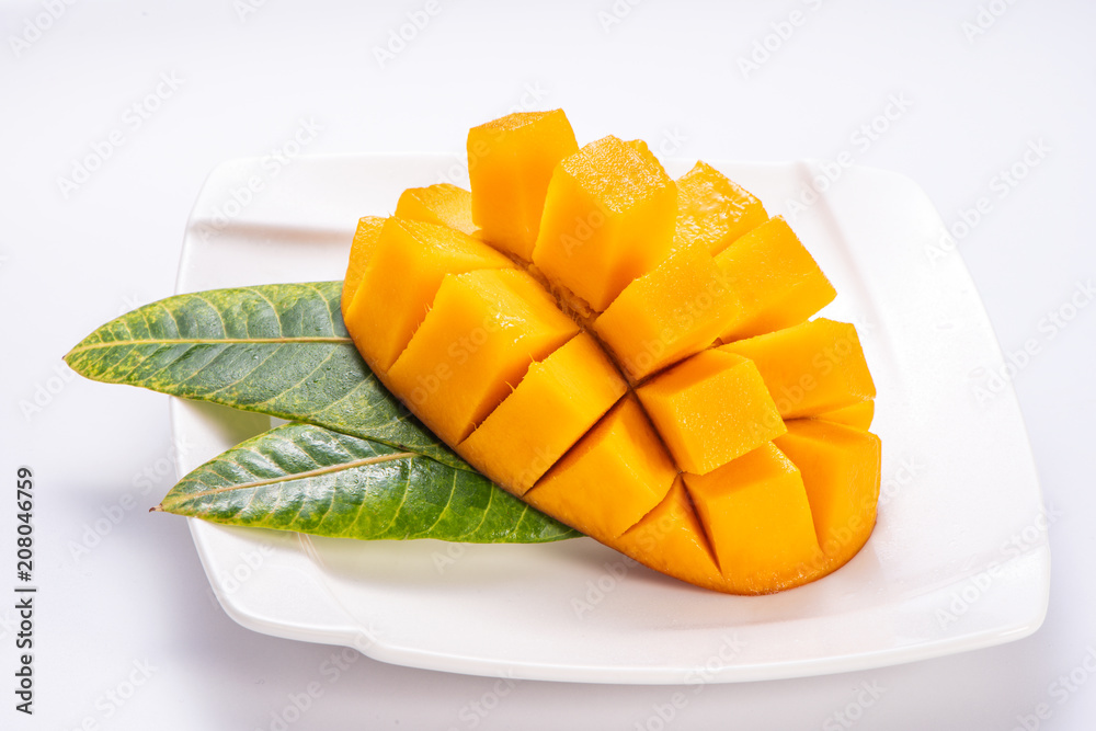 Fresh and beautiful mango in a white plate with sliced diced mango chunks isolated with white background, copy space(text space), blank for text Fresh and beautiful mango in a white plate with sliced diced mango chunks isolated with white background, copy space(text space), blank for text
