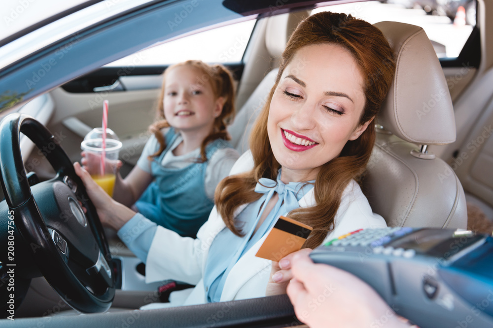 smiling businesswoman paying with credit card for take away order in car smiling businesswoman paying with credit card for take away order in car