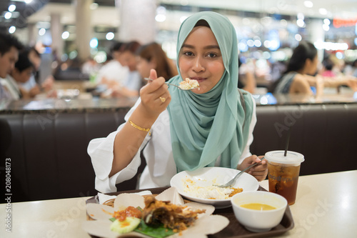 a muslim girl eating Indonesian cuisine 