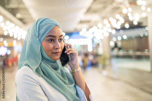 asian muslim girlusing smartphone inside mall