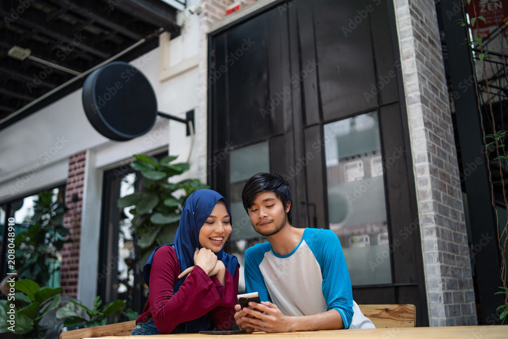 a muslim married couple in a cafe with a laptop a muslim married couple in a cafe with a laptop
