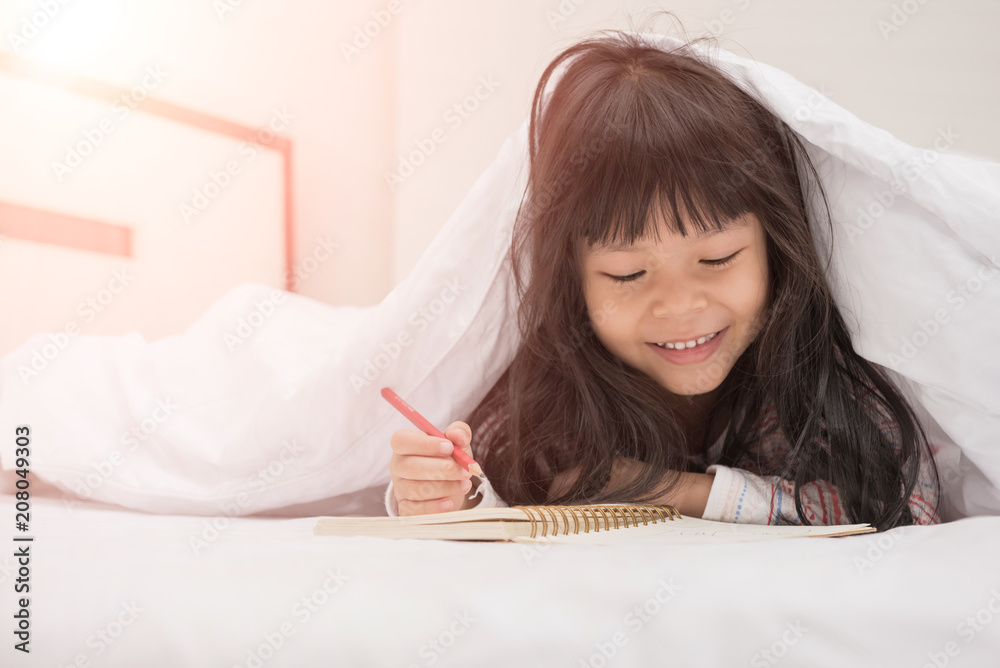 little girl lying on the bed and reading a book little girl lying on the bed and reading a book