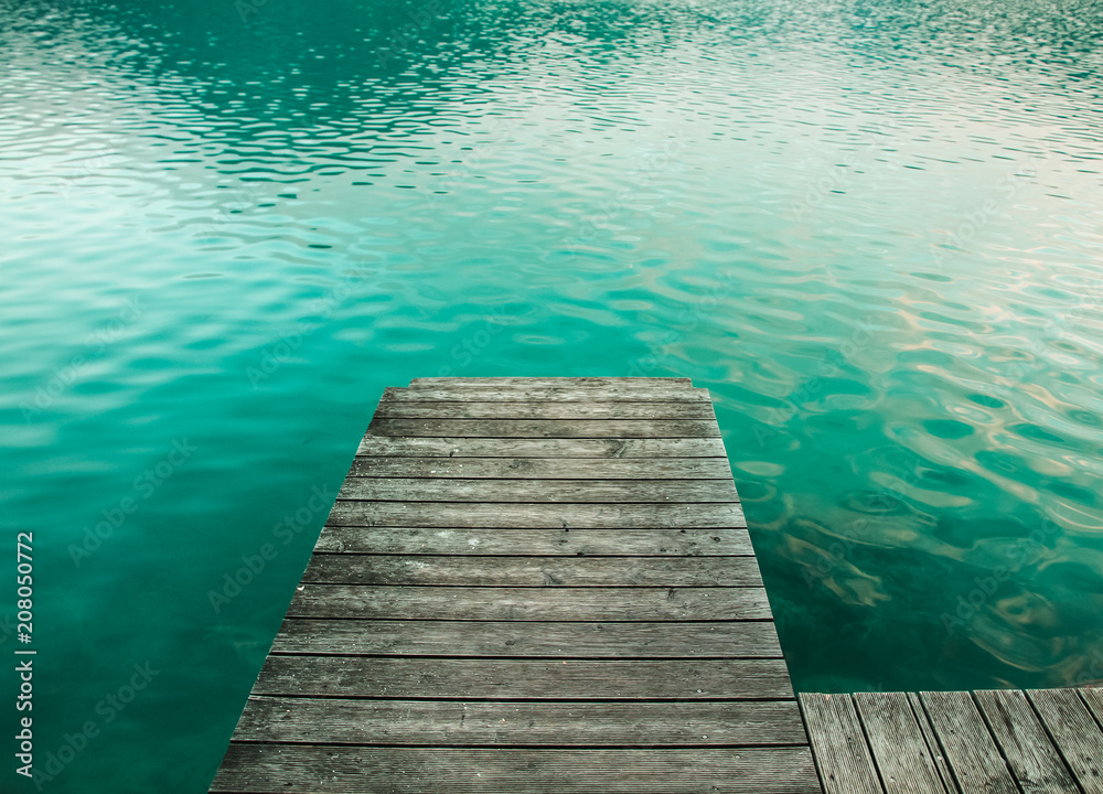 Wooden platform as bridge pier deck on an alpine lake with beautiful green turquoise clear water during summer in Austria. Wooden platform as bridge pier deck on an alpine lake with beautiful green turquoise clear water during summer in Austria.