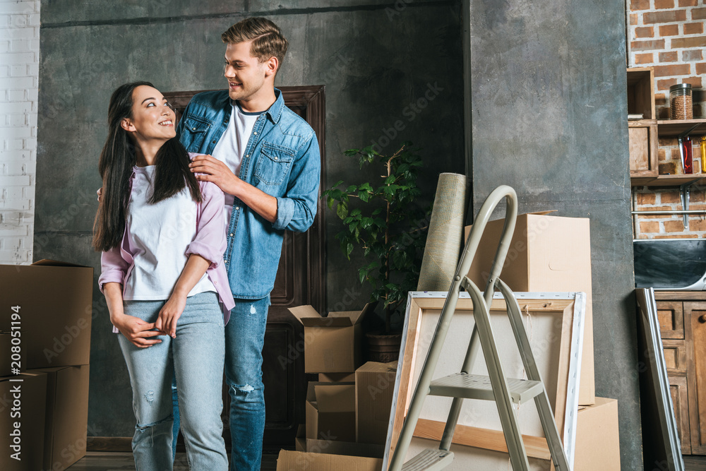 smiling interracial couple with boxes moving into new home smiling interracial couple with boxes moving into new home