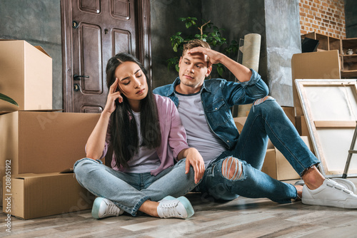 young couple sitting on floor after argument while moving into new home