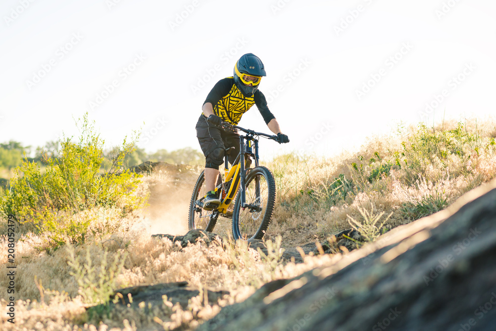Cyclist Riding the Mountain Bike on the Summer Rocky Trail at the Evening. Extreme Sport and Enduro Cycling Concept. Cyclist Riding the Mountain Bike on the Summer Rocky Trail at the Evening. Extreme Sport and Enduro Cycling Concept.