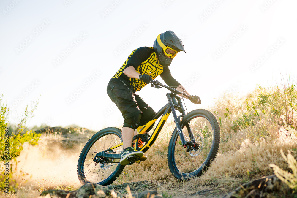 Cyclist Riding the Mountain Bike on the Summer Rocky Trail at the Evening. Extreme Sport and Enduro Cycling Concept. Cyclist Riding the Mountain Bike on the Summer Rocky Trail at the Evening. Extreme Sport and Enduro Cycling Concept.