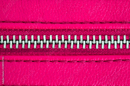 Pink zipper tightly closed binding together two layers of fabric textile and leather under high magnification close detail photography as texture background.