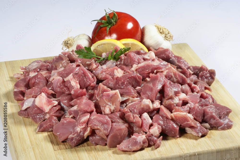 Raw chopped lamb meat on a wooden cutting board on a slate