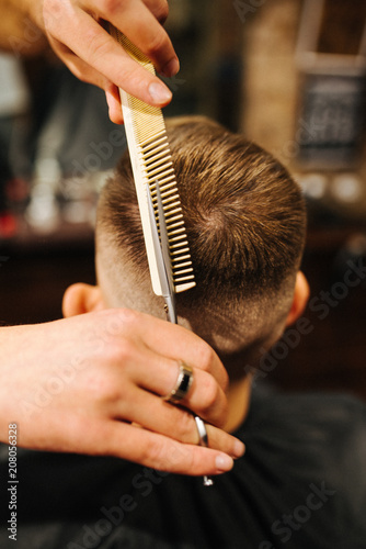 Hairdresser blow drying his client in barbershop. Barber using scissors and comb