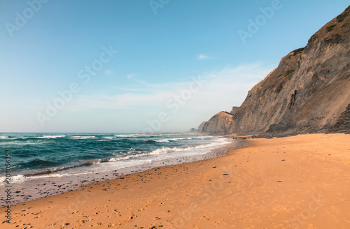 Fototapeta Naklejka Na Ścianę i Meble -  A deserted beach with volcanic cliff and the blue green waters of the Atlantic Ocean in Sagres, Algarves, Portugal during Summer.