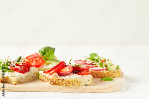 various fresh sandwiches on cutting board and on white surface