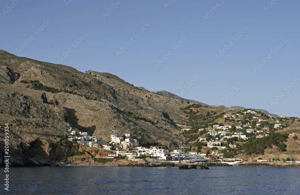 The mountain shore of Mediterranean sea and the town with white houses in the sunny day. It is the view from the sea ferry.
