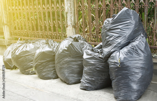 black garbage bags on the ground to await disposal with sunlight