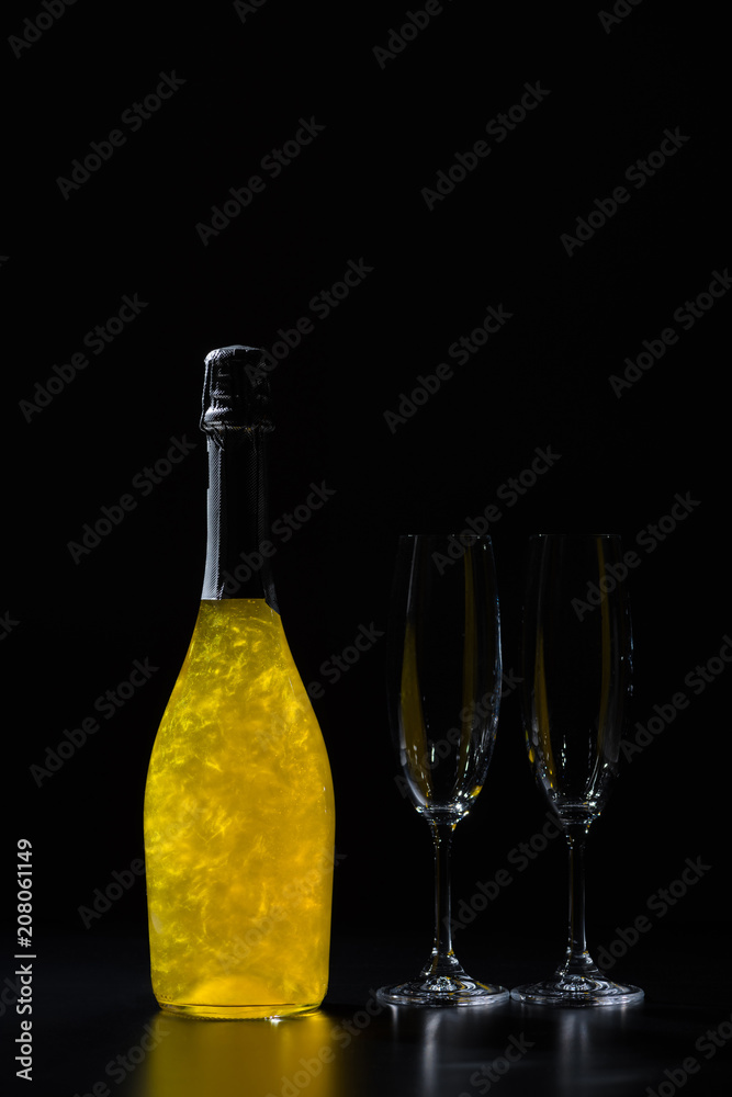 close up view of bottle of champagne and empty glasses on black background