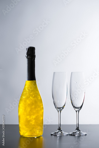 close up view of bottle of champagne and empty glasses on grey background