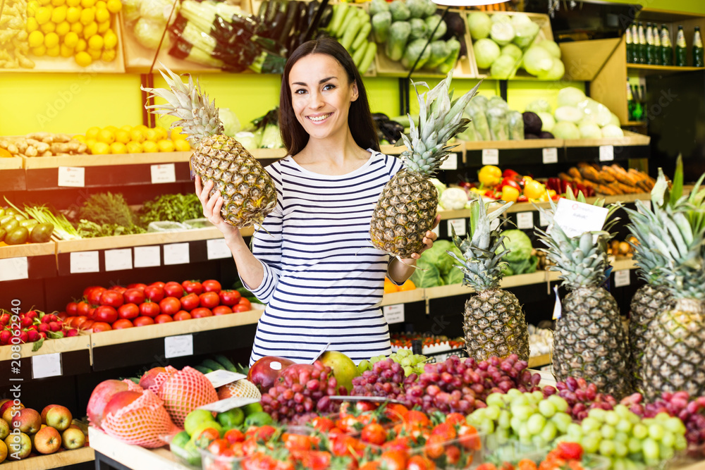 Attractive smiling young girl in casual clothes selects fruits and vegetables from a shelf in a grocery store. Attractive smiling young girl in casual clothes selects fruits and vegetables from a shelf in a grocery store.