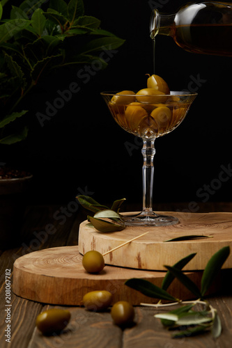 vintage glass with olives and oil on stacked boards