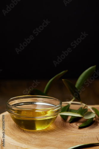olive oil in bowl with branch on wooden board