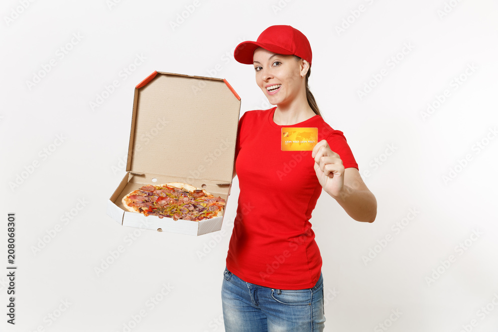 Delivery woman in red uniform isolated on white background. Female in cap, t-shirt, jeans working as courier holding italian pizza in cardboard flatbox and credit card. Copy space for advertisement. Delivery woman in red uniform isolated on white background. Female in cap, t-shirt, jeans working as courier holding italian pizza in cardboard flatbox and credit card. Copy space for advertisement.